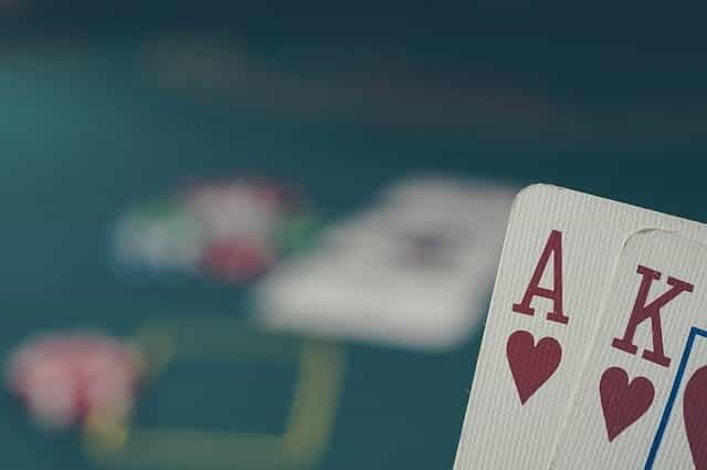 Ace-king of hearts in front of a poker table with chips on.