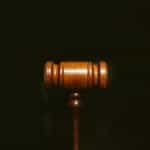 A wooden gavel sits on a black surface.