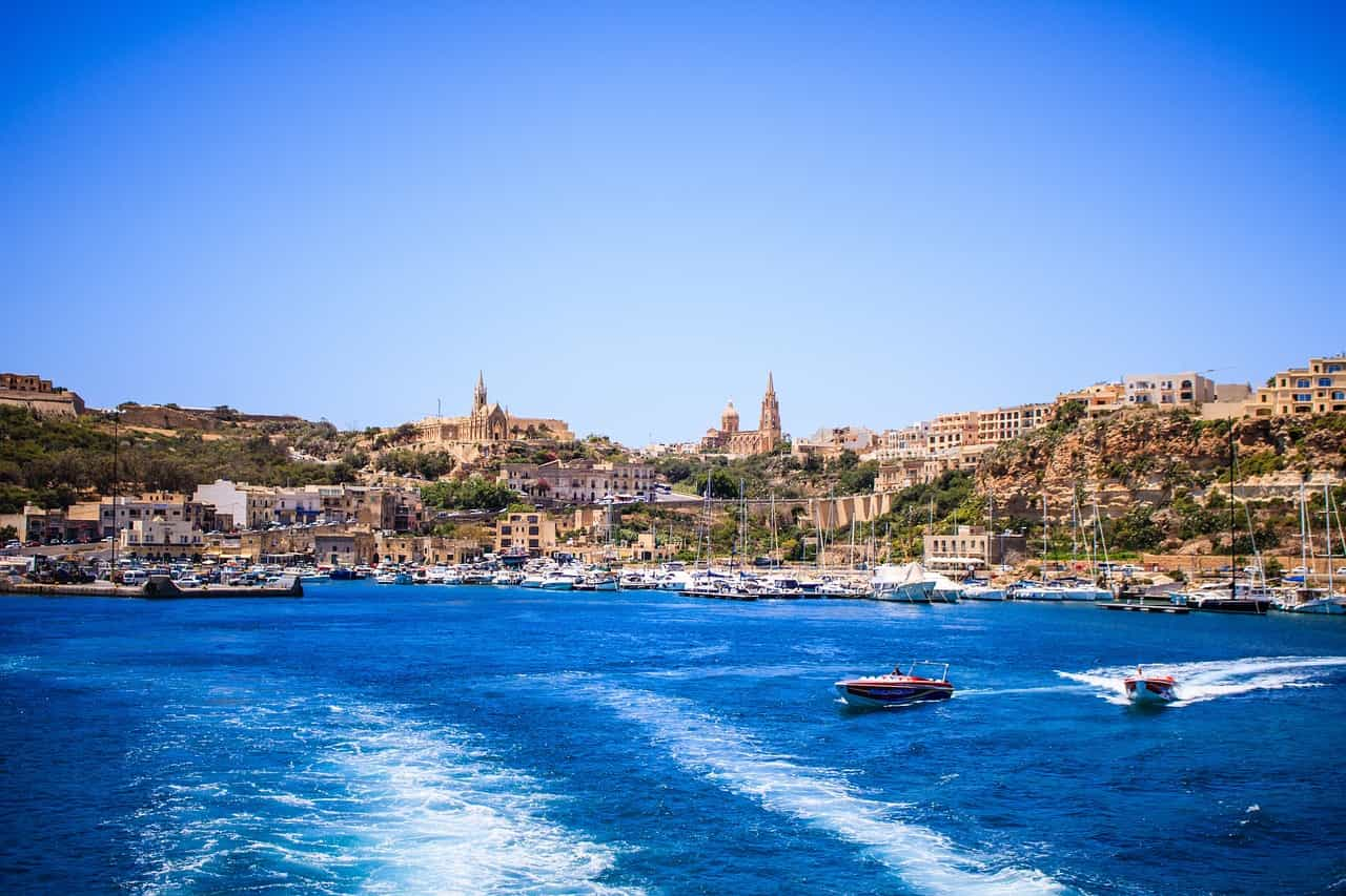 A marina with boats and buildings on the shore. 